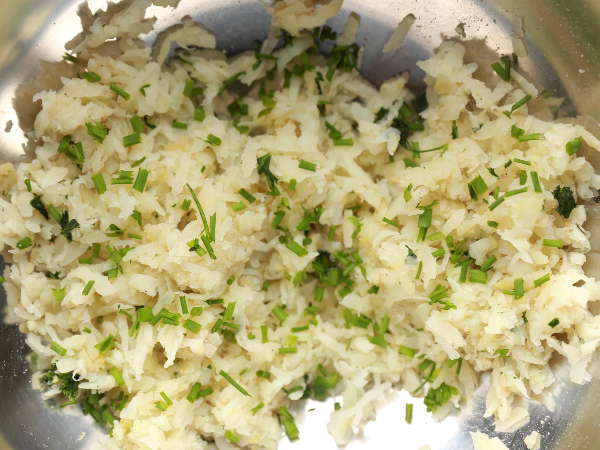 Season the grated potato with salt, pepper, parsley and chives for the easy latke.