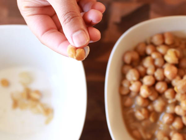 Peel the skin of cooked garbanzo beans for Spicy Green Hummus.